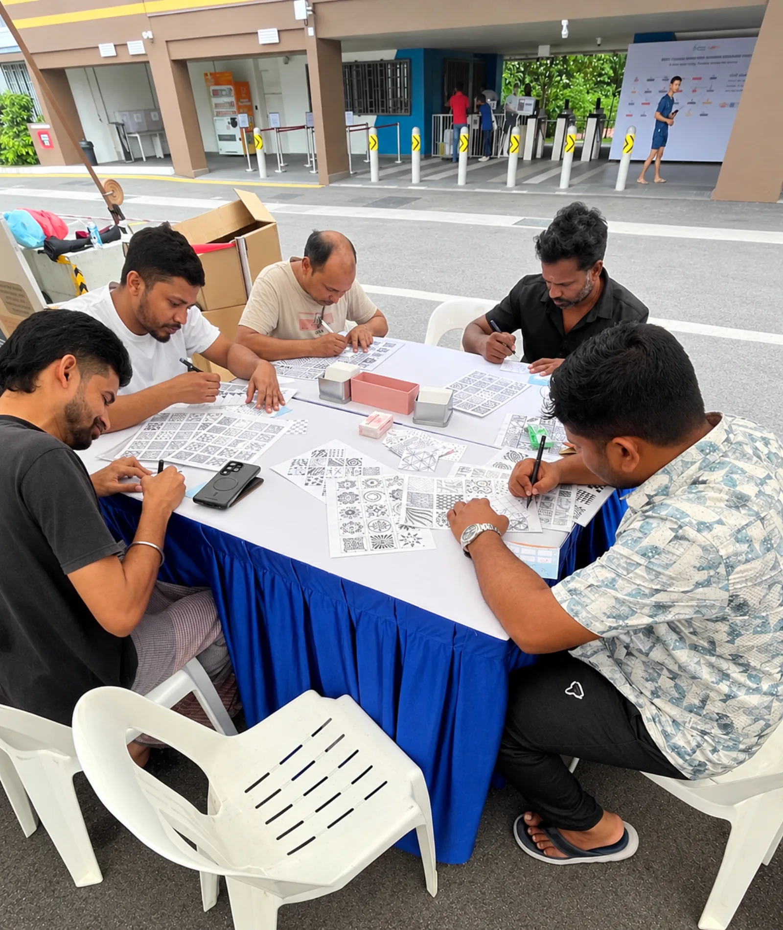 Five participants seated around a table, writing on activity sheets during an outdoor session